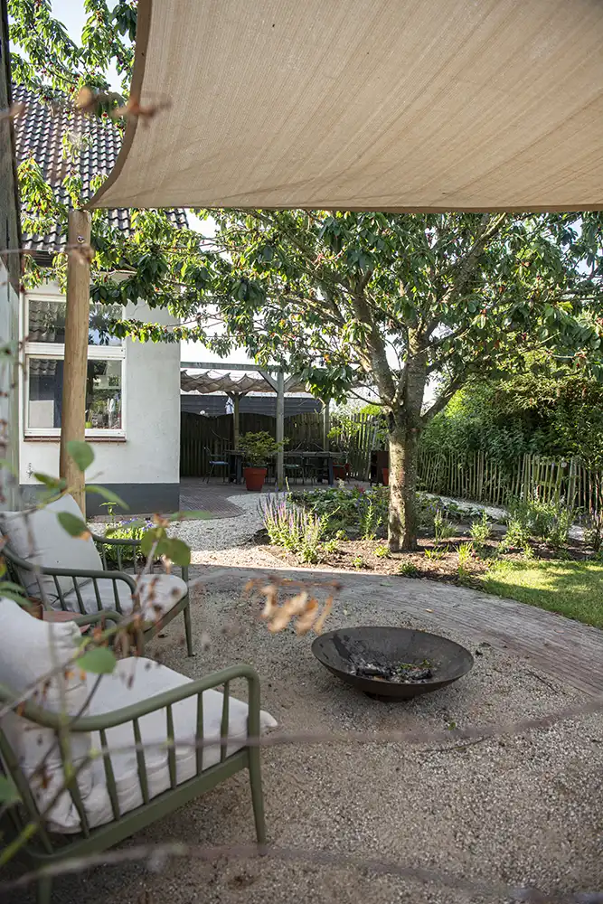 Tuin met schaduwdoek, grind en vuurschaal
