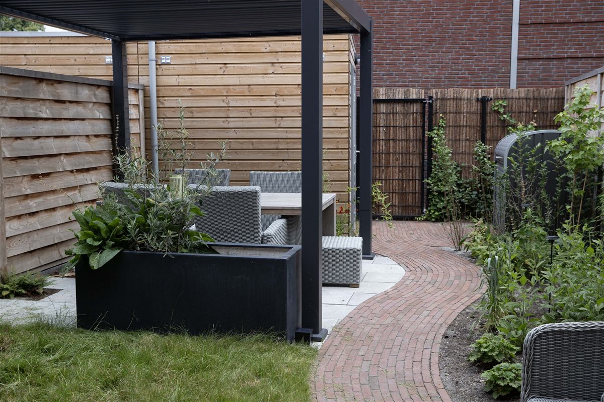 Overkapte zithoek met gebakken klinkerpad en borders